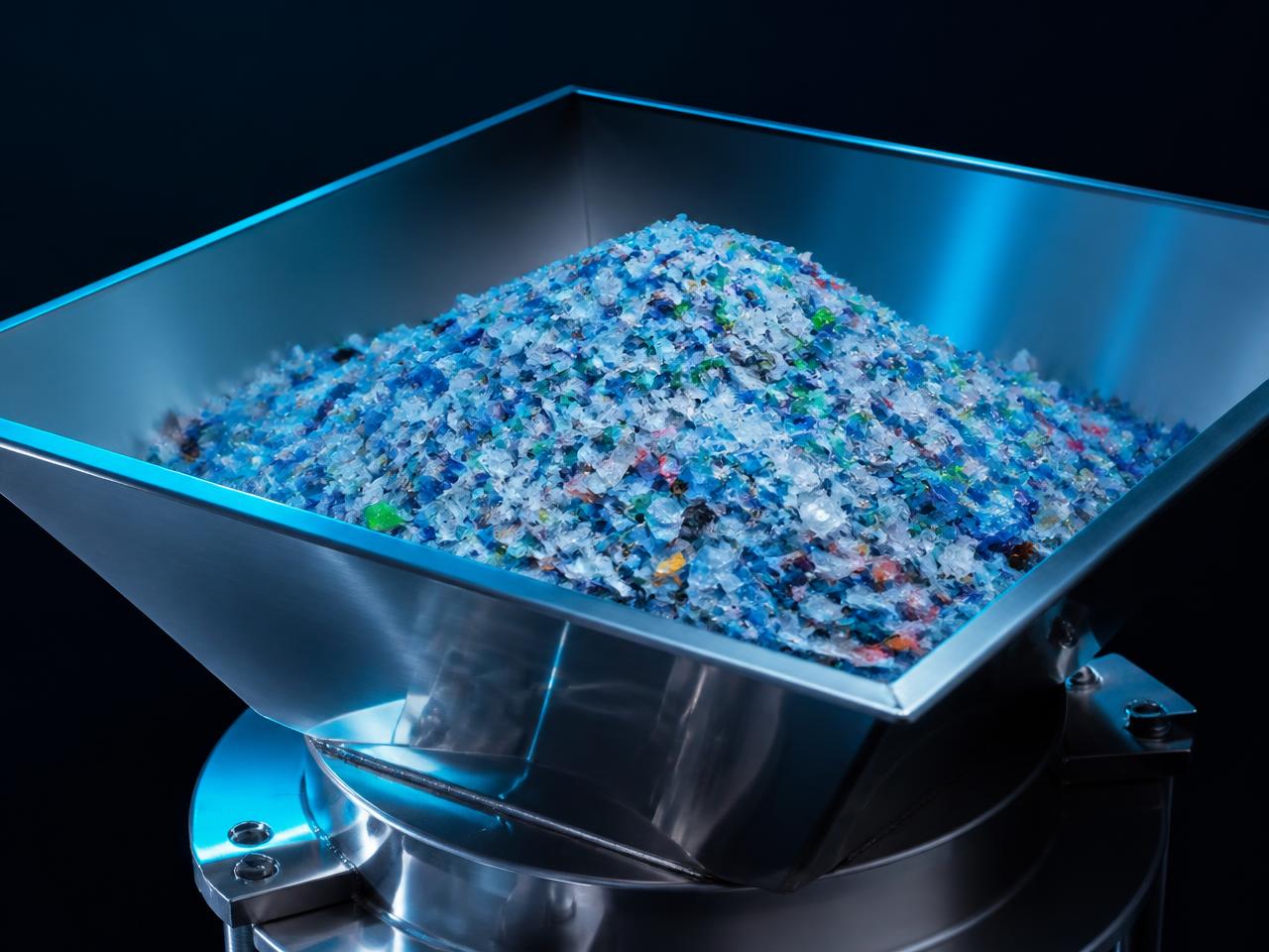 Shredded mixed plastic flake feedstock in a stainless steel hopper